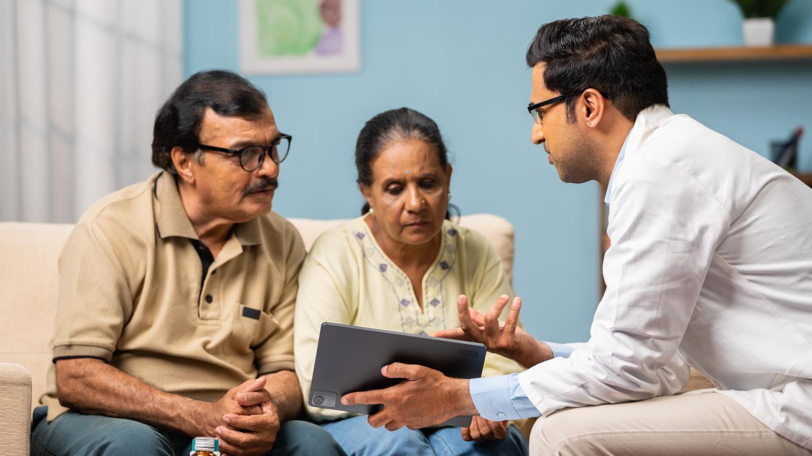 Healthcare professional discussing a care plan with an older couple during an in-home consultation